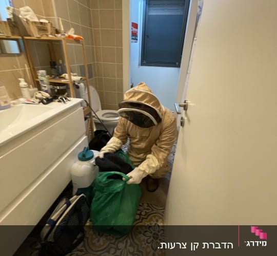 אדם בחליפת מגן עם ציוד הדברה בחדר אמבטיה